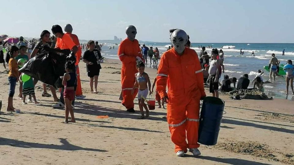 Los aliens recorrieron la playa para recoger basura y dar regalo a los niños.