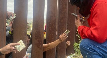 Repartidores llevan comida 'a domicilio' a migrantes en muro fronterizo